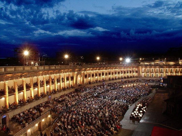 Foto van het theater Il Sferisterio in Marcerata in de avond met sfeervolle verlichting tijdens een voorstelling.